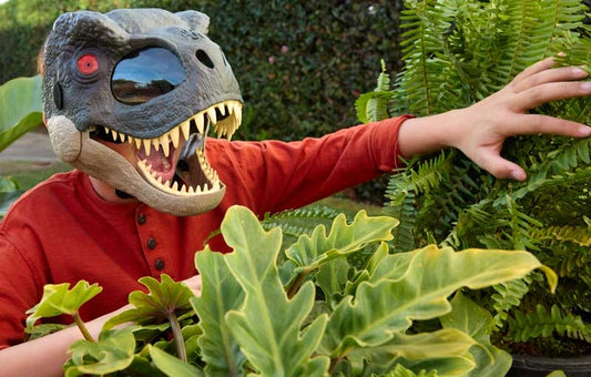 Person wearing a dinosaur mask among green plants