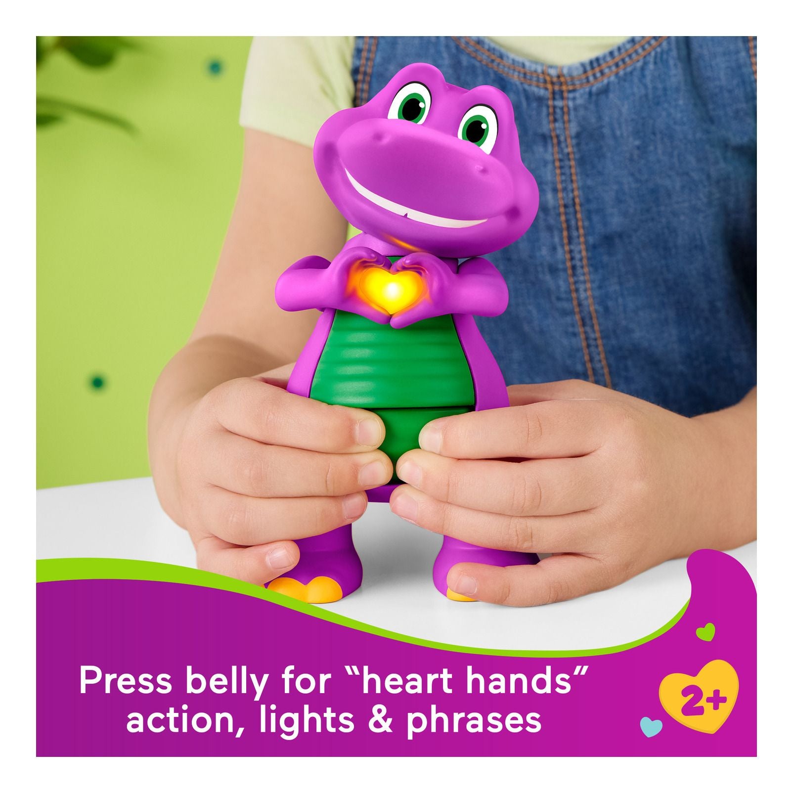 Purple dinosaur toy with green belly held by a child against a white background