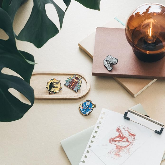 Colorful pins on a wooden tray with a notebook, pen, and plant in the background