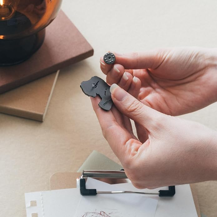 Person using a paper punch on a piece of paper with a small object held in hand.