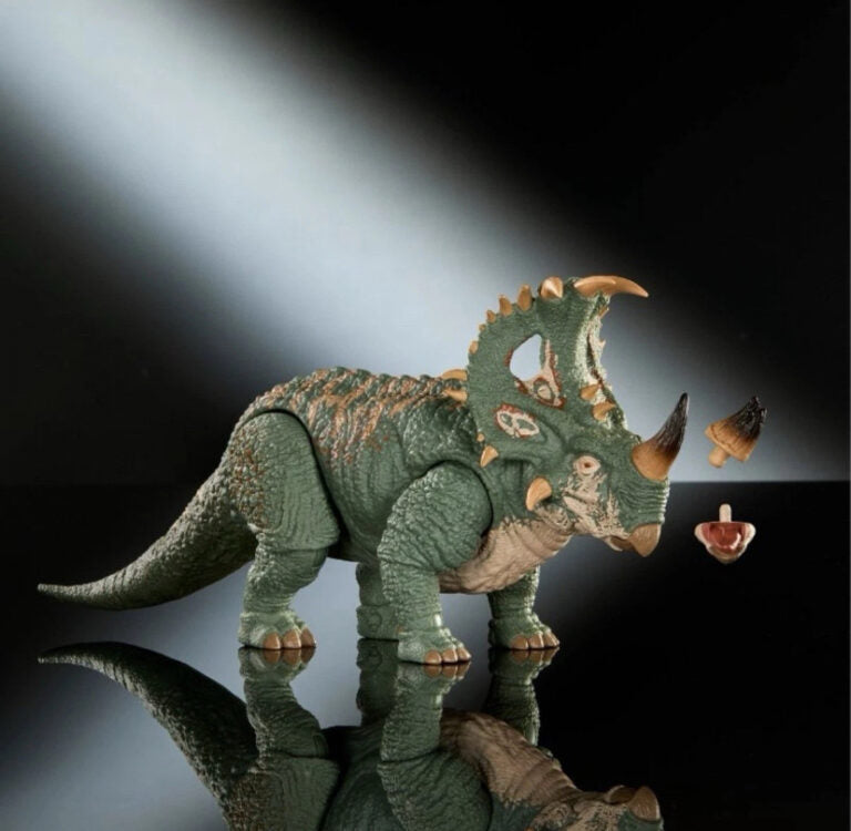 Toy triceratops dinosaur on a reflective surface with a dark background