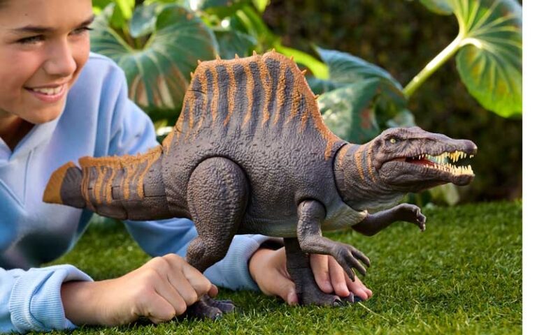 Child playing with a toy Spinosaurus on grass