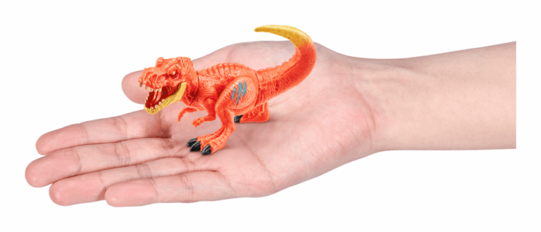 Small orange dinosaur toy held in a hand on a white background